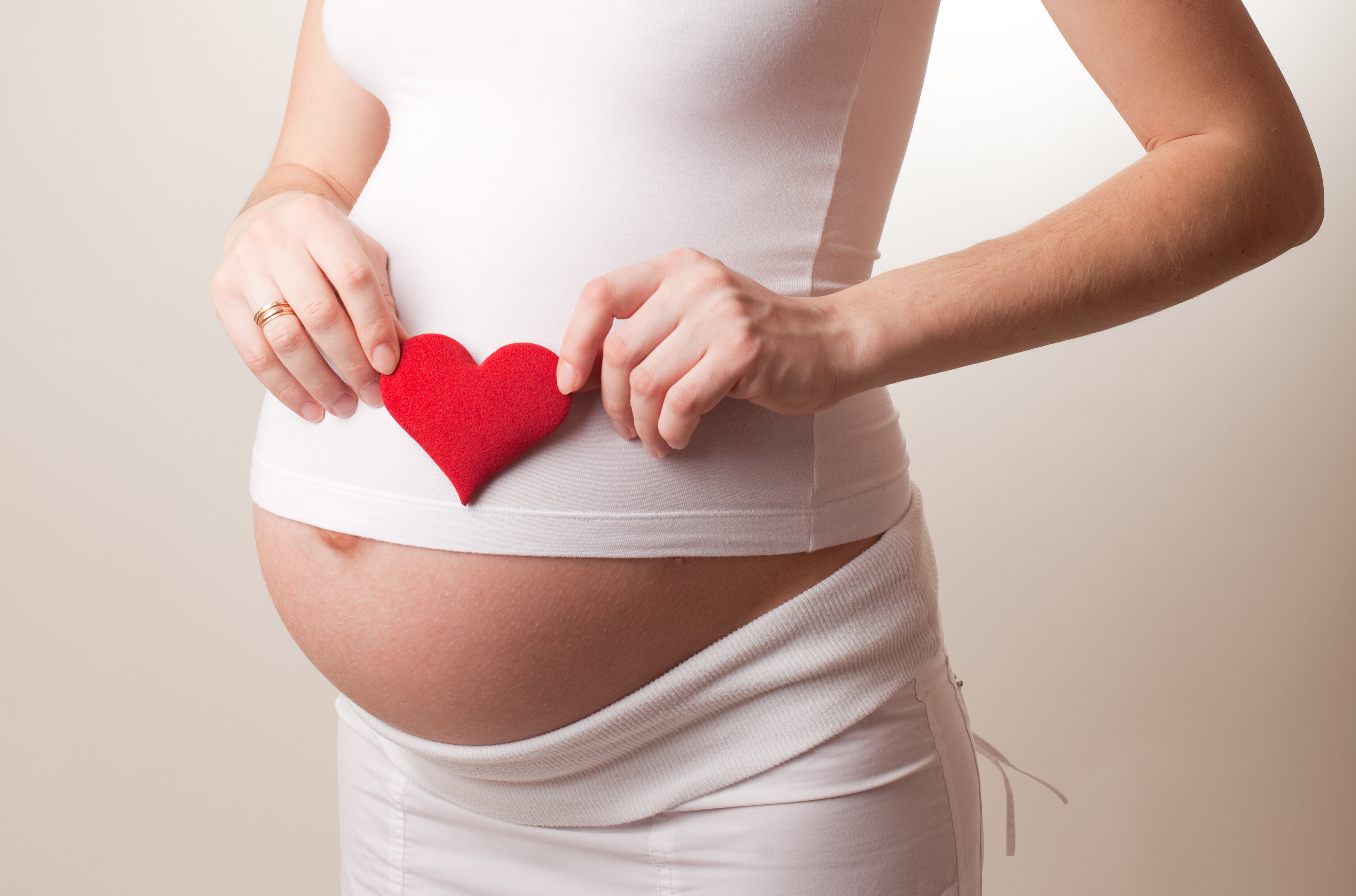 woman holding a heart icon over her pregnant belly