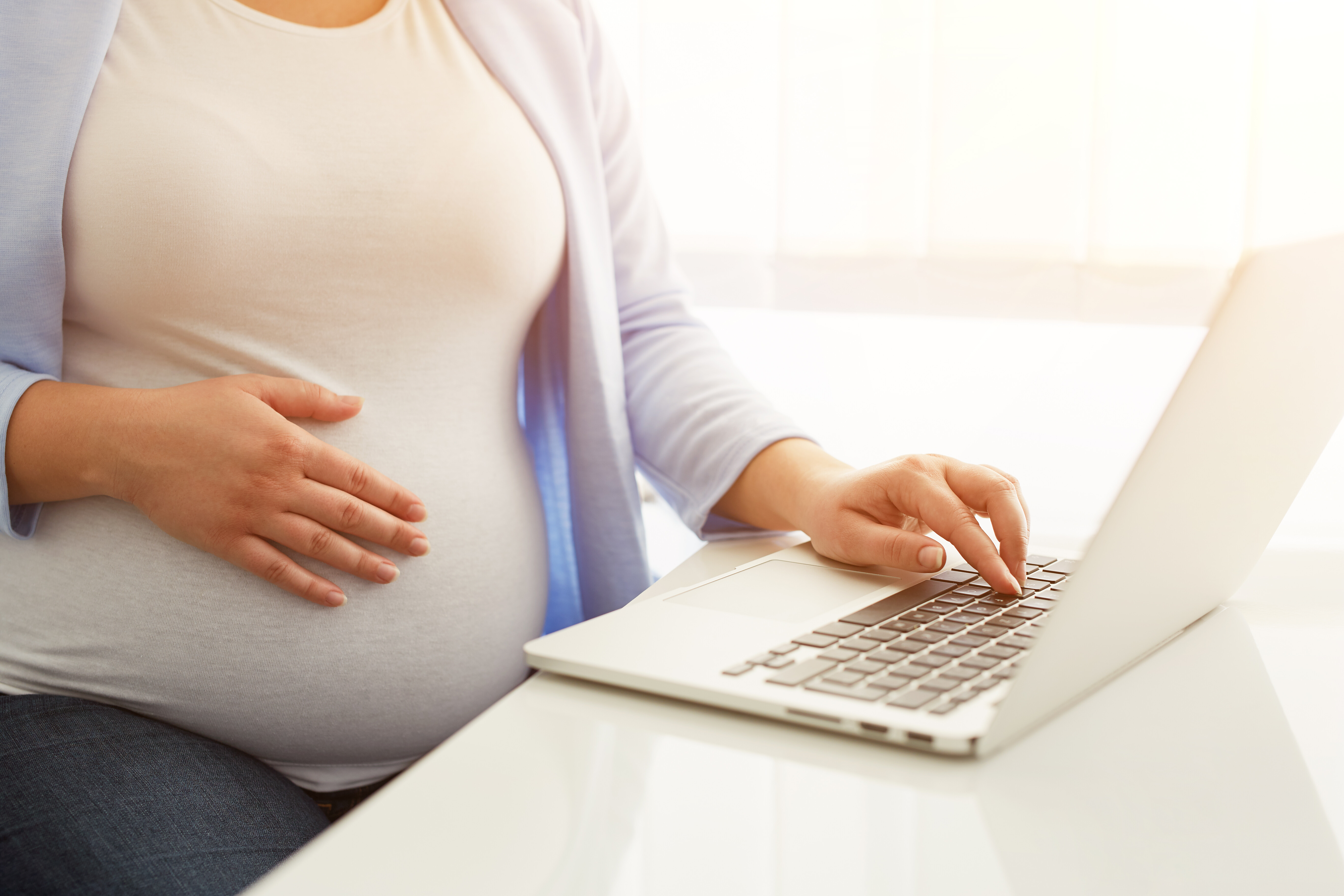 pregnant woman googling how do you find a surrogate mother on laptop