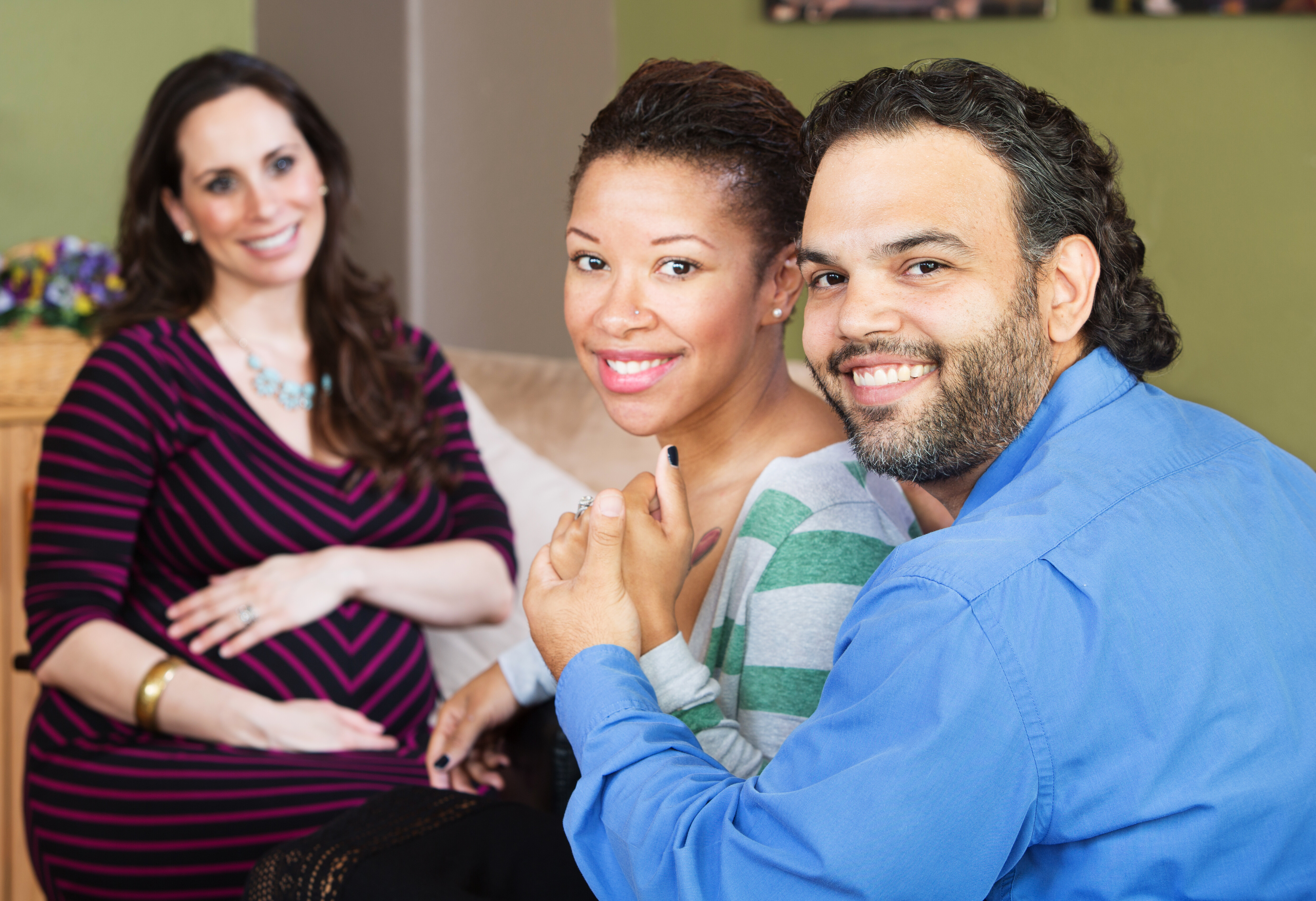 Married couple holding hands next to a pregnant woman