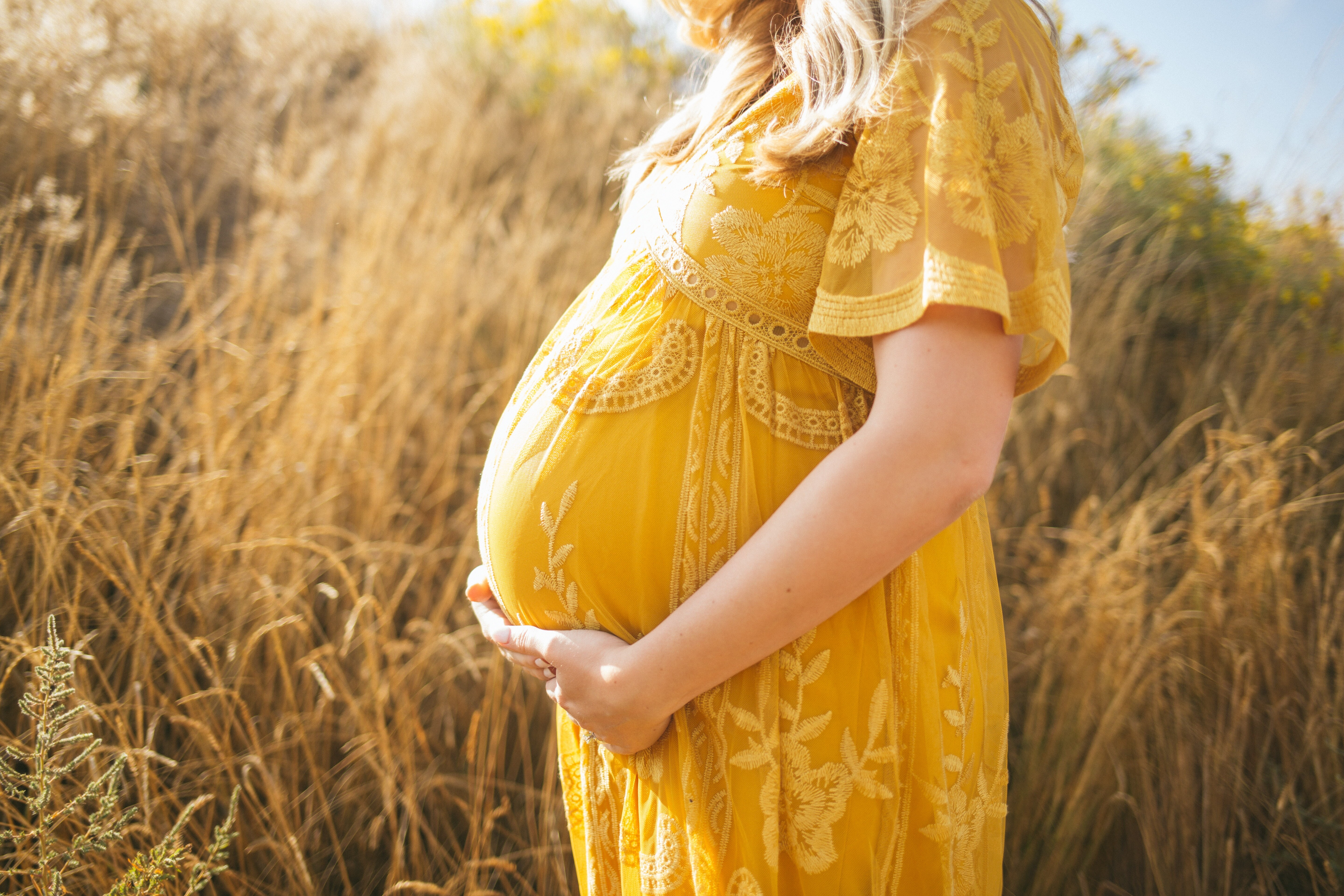 surrogate mother in yellow dress in field