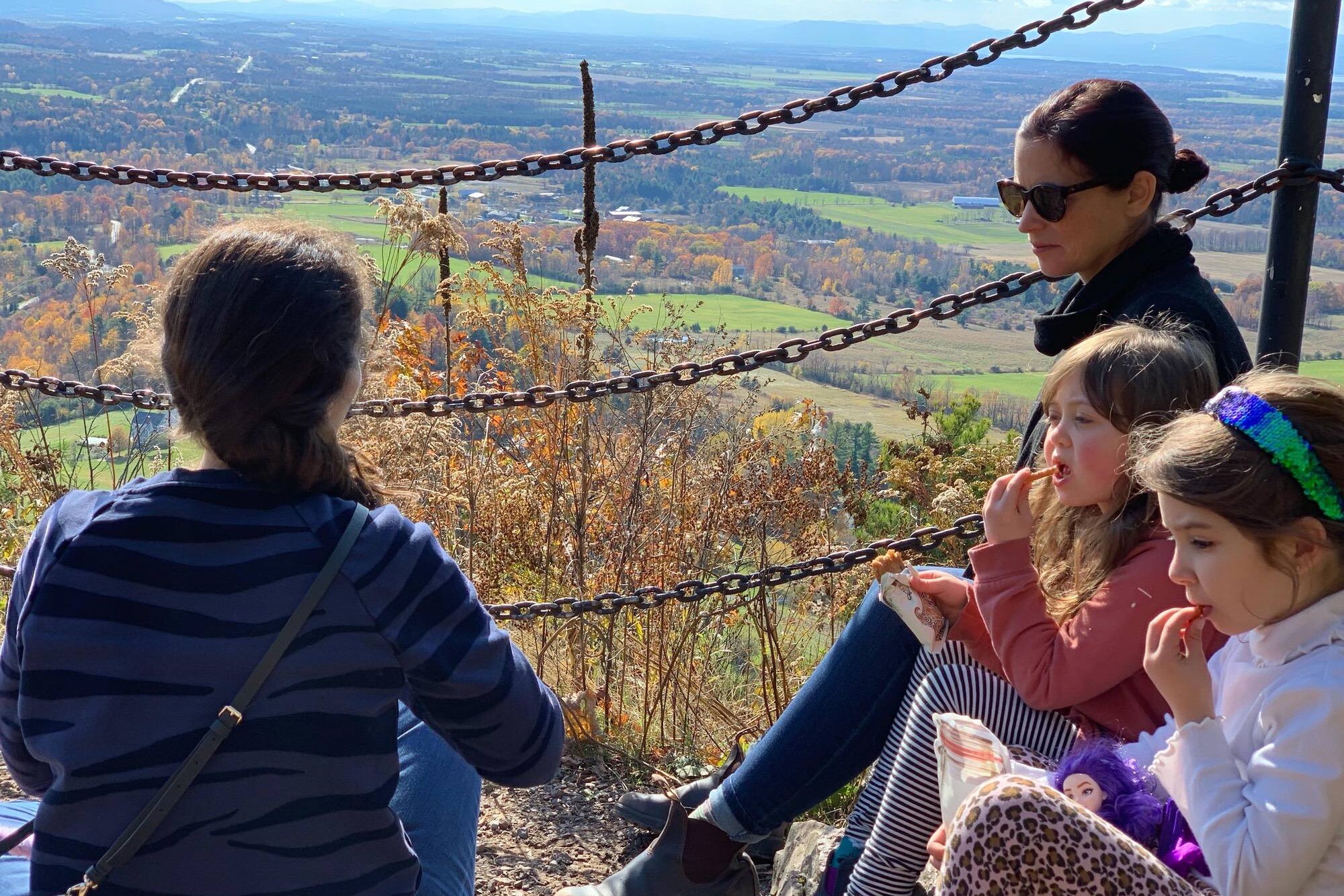 Mothers sitting with their two young girls overlooking Vermont foliage scene