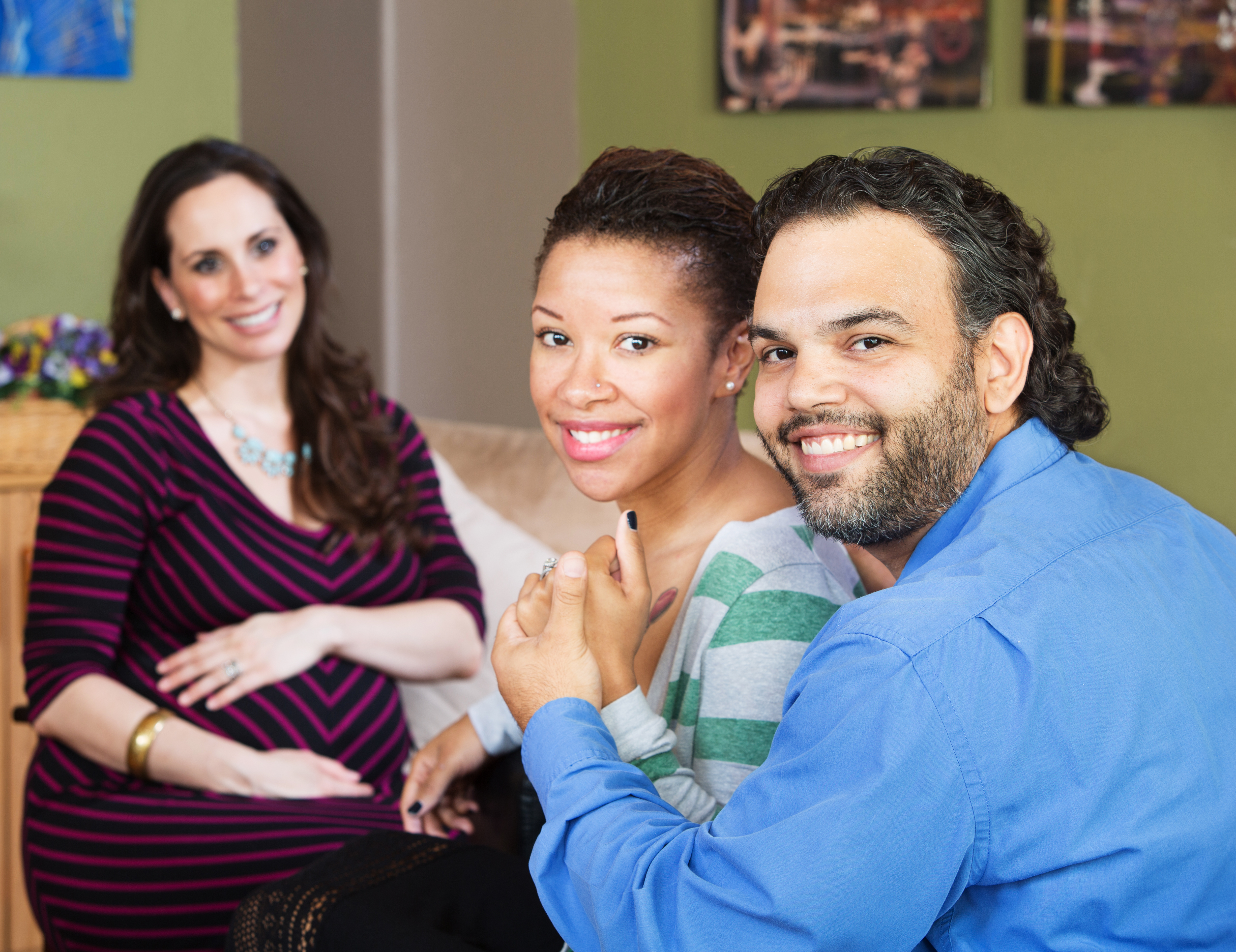 Married couple holding hands next to a pregnant woman