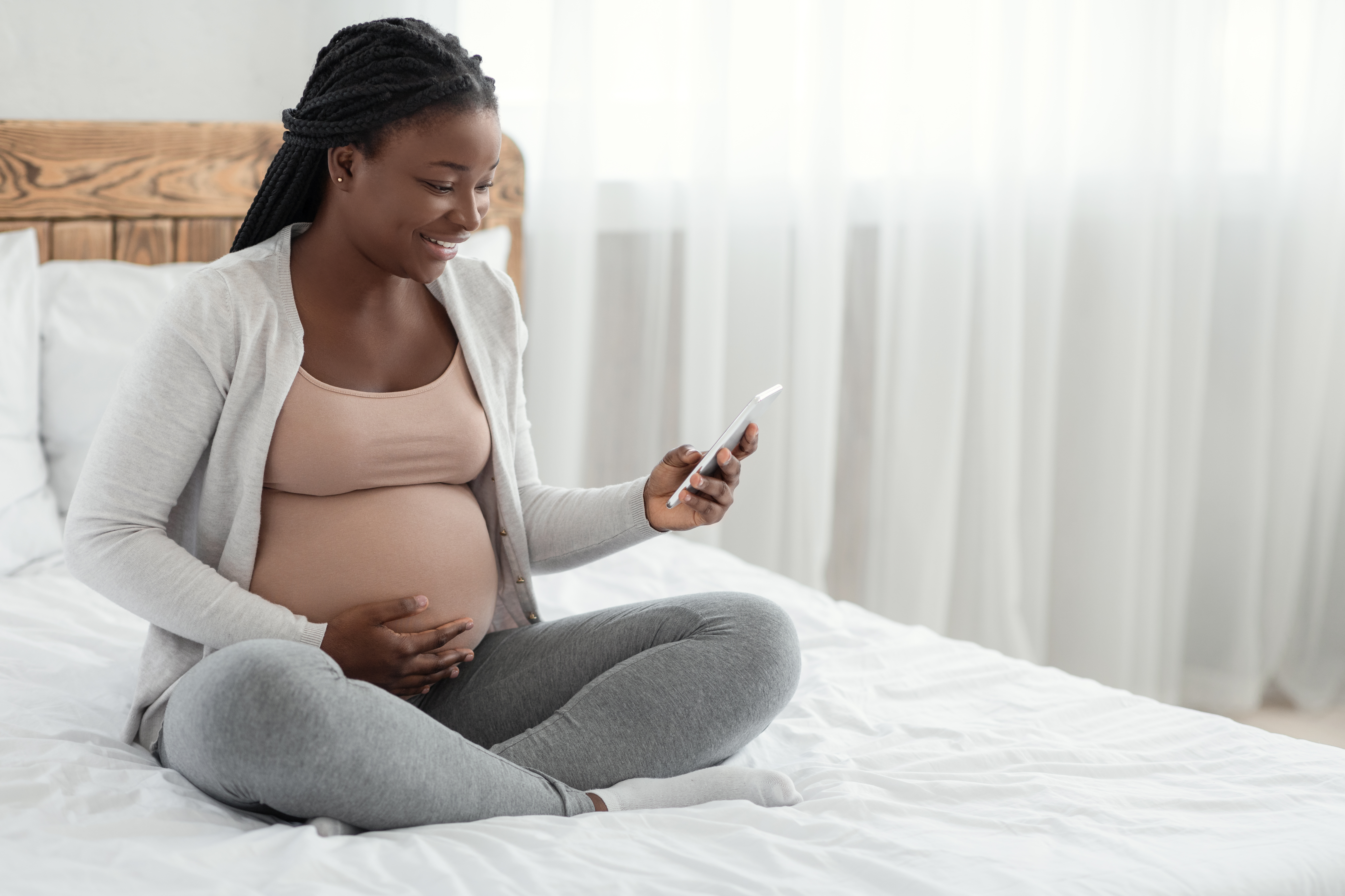 woman sitting on bed looking up the surrogacy process on her phone